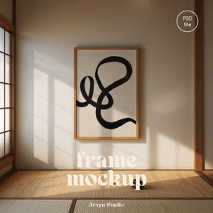 Op de afbeelding: Een ingelijste kunstdruk met een zwart abstract ontwerp op een witte achtergrond. Het kunstwerk wordt gepresenteerd in een licht houten frame, tegen een neutrale muur. De woorden "frame mockup" staan eronder. De afbeelding is in een kamer met een tatami-mat.