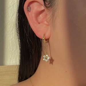 May include: Gold hoop earrings with a dangling star charm featuring clear cubic zirconia stones.