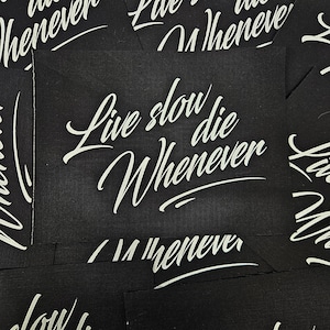 May include: Close-up of several black fabric patches with white text that reads "Live slow die whenever".