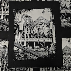 May include: Black and white image of a ruined building with a large tree trunk lying across the front. The building has a large arched window and a balcony. The image is in a distressed style, with a black border and a white background.