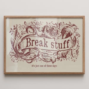 Puede incluir: Impresión enmarcada con las palabras "Break stuff" en una pancarta, rodeada de adornos y elementos florales en color burdeos. La frase "-it's just one of those days-" está debajo. La impresión está en un marco de madera marrón claro.