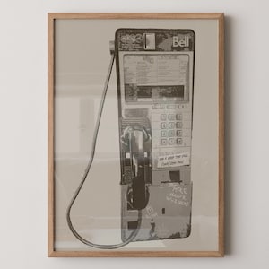 Może przedstawiać: Oprawiony wydruk zabytkowego automatu telefonicznego Bell w odcieniach sepii. Telefon posiada klawiaturę, słuchawkę i zwinięty przewód. Graffiti na telefonie głosi "Mike Hawk Wuz Here", a naklejka głosi "For a good time call (545) 254-1412".