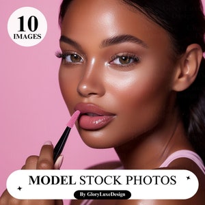 Op de afbeelding: Een vrouw met donkerbruine huid en donker haar brengt roze lipgloss aan met een transparante applicator. Ze draagt een roze tanktop en heeft een natuurlijke make-up look. De achtergrond is lichtroze.