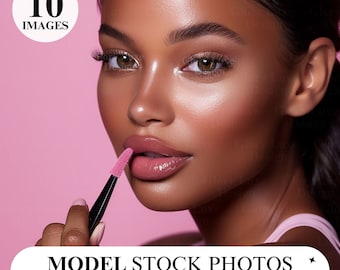 May include: A woman with dark brown skin and dark hair is applying pink lip gloss with a clear applicator. She is wearing a pink tank top and has a natural makeup look. The background is a light pink.