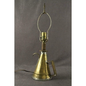 May include: A brass lamp made from a repurposed oil can with a simple, curved lampshade. The lamp has a handle and a spout.