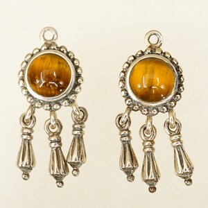 May include: A pair of silver earrings with a round tiger's eye gemstone and three dangling silver tassels.