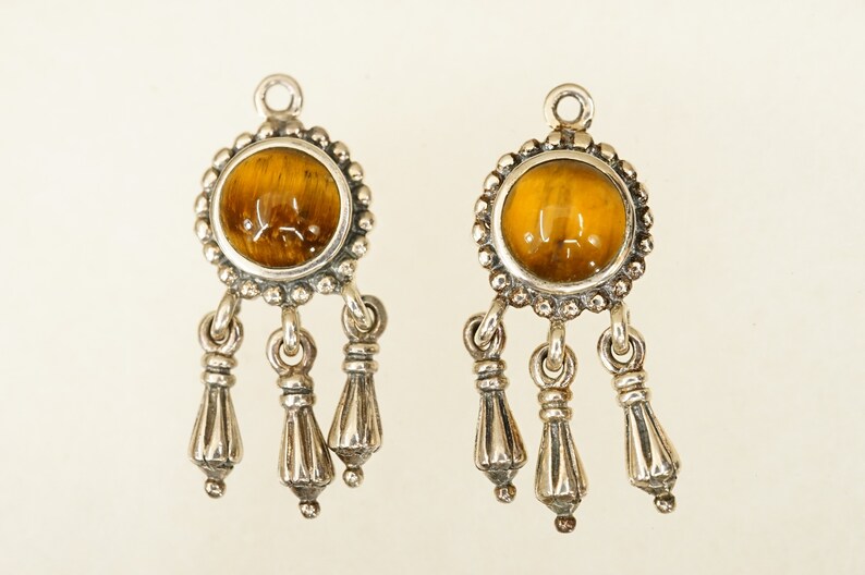 May include: A pair of silver earrings with a round tiger's eye gemstone and three dangling silver tassels.