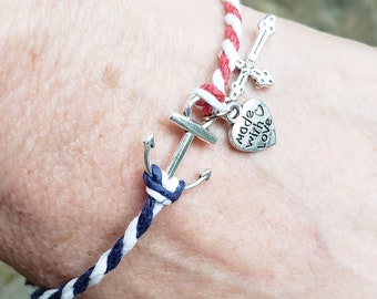 May include: A white, red, and blue braided bracelet with a silver anchor charm and a silver heart charm that says "Made with Love".