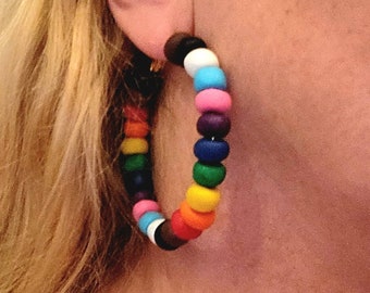 May include: Rainbow colored beaded hoop earrings. The beads are round and are in the order of red, orange, yellow, green, blue, purple, pink, white, black, white, light blue, pink, purple, dark blue, green, yellow, orange, red.