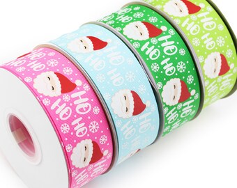 May include: Four spools of grosgrain ribbon in pink, light blue, green, and lime green. Each ribbon features a repeating pattern of Santa Claus faces with red hats, white snowflakes, and the white text "HO HO HO" printed across the surface.