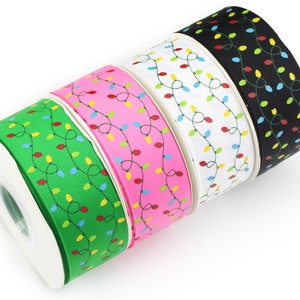 May include: Four spools of grosgrain ribbon arranged in a row, each featuring a repeating pattern of thin, dark green wavy lines with small, colorful light bulb icons in red, yellow, blue, and green against green, pink, white, and black backgrounds.
