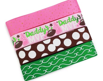 May include: Three strips of grosgrain ribbon stacked vertically. The top ribbon is pink with gold glitter. The middle ribbon is pink with the text Daddy's MVP, footballs, and foam fingers. The bottom ribbon is brown with white polka dots and green with white swirls.