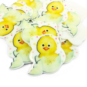 May include: A collection of flat, die-cut embellishments featuring a yellow chick hatching from a light green eggshell. Each piece is decorated with small, colorful polka dots in pink, yellow, and green, showcasing a cartoon-style illustration.