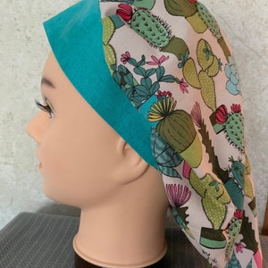 May include: A white scrub hat with a turquoise trim and a cactus print. The hat is made of a soft, comfortable fabric and is ideal for nurses, doctors, and other healthcare professionals.