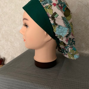 May include: A green and white scrub hat with a cactus print. The hat has a green band around the bottom.