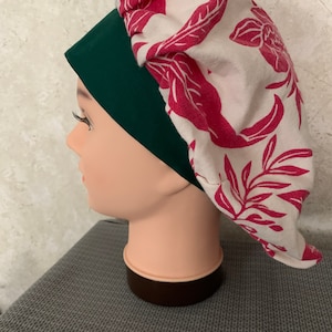 May include: A white and pink floral print fabric sleep cap with a dark green fabric lining. The cap is on a mannequin head.