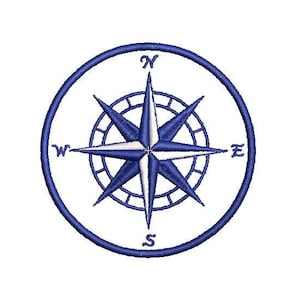 May include: A navy blue embroidered compass rose design, featuring directional points N, S, E, and W. The compass rose is enclosed within a circular frame, with a detailed starburst pattern at its center. The design is set against a white background.