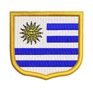 Pode incluir: Um remendo bordado em ouro com a bandeira do Uruguai. A bandeira tem um fundo branco com nove listras horizontais azuis e um sol amarelo no canto superior esquerdo.