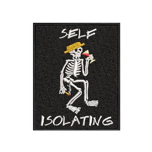 Puede incluir: Un parche bordado negro con un esqueleto blanco que lleva un sombrero amarillo, sosteniendo una bebida y un cigarrillo. El texto "SELF ISOLATING" está escrito debajo del esqueleto.