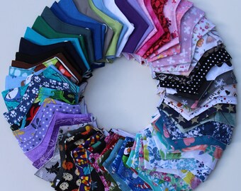 May include: A collection of colorful fabric face masks arranged in a circle. The masks are made of various patterns and colors, including blue, green, red, and white.