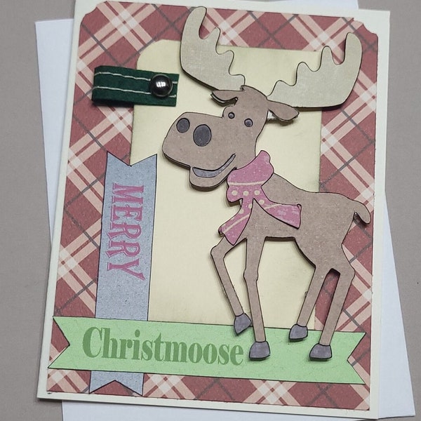 Puede incluir: Una tarjeta de Navidad con un fondo a cuadros que presenta un alce de dibujos animados con una bufanda rosa. La tarjeta tiene una pancarta que dice "Merry Christmoose".