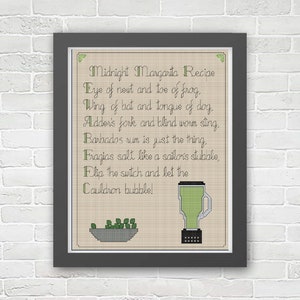 May include: A framed cross-stitch pattern with a beige background and green text. The text reads "Midnight Margarita Recipe" and includes a list of ingredients. The image also includes a green blender and a bowl of green peas.