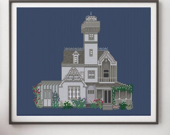 May include: A cross-stitch pattern of a white house with a tower, surrounded by green bushes and flowers. The house has a gray roof and brown accents. The background is a dark blue.