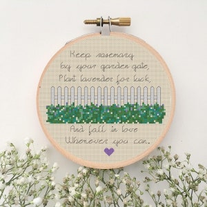 May include: A white picket fence with green bushes and purple flowers behind it. The text reads "Keep rosemary by your garden gate, plant lavender for luck, and fall in love whenever you can."