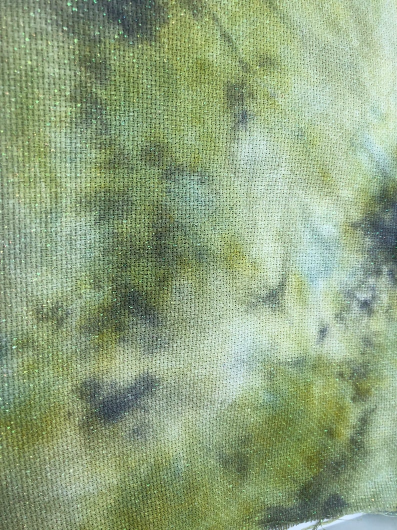 K&ouml;nnte beinhalten: Nahaufnahme eines gr&uuml;nen und braunen Stoffes mit einer strukturierten Oberfl&auml;che. Der Stoff hat ein Batik-Muster in Gr&uuml;n-, Braun- und Wei&szlig;t&ouml;nen.