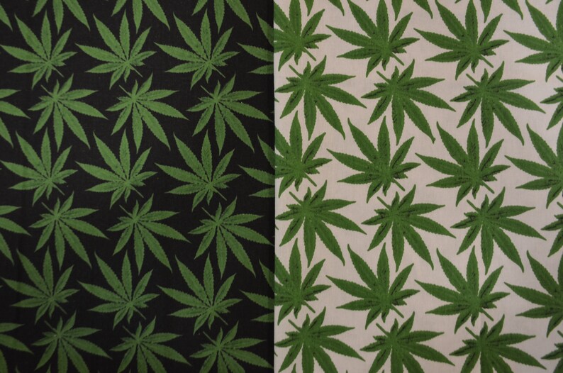 May include: A fabric with a repeating pattern of green marijuana leaves on a black background on the left side and a white background on the right side.