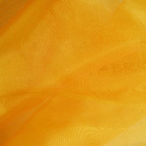 May include: A close-up of a bright yellow sheer fabric. The fabric has a slight sheen and is very lightweight.