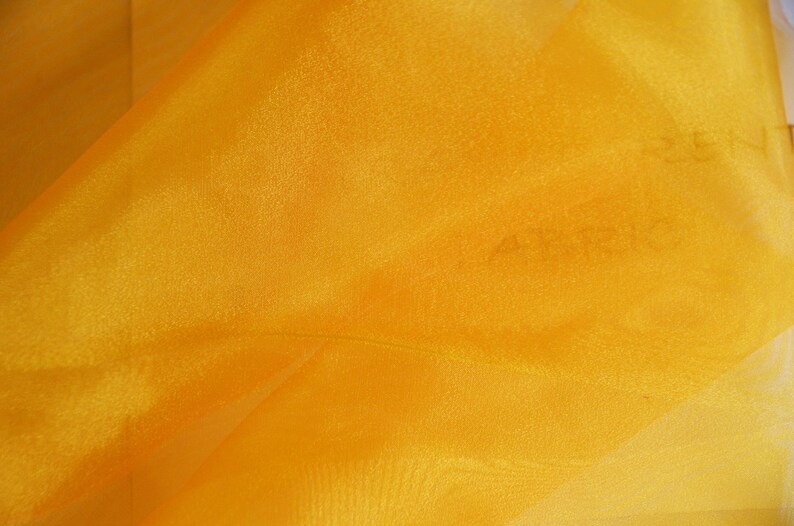 May include: A close-up of a bright yellow sheer fabric. The fabric has a slight sheen and is very lightweight.