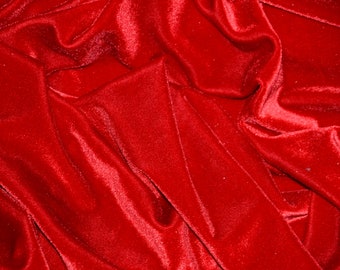 May include: Close-up of a deep red velvet fabric with soft, flowing folds. The fabric has a luxurious and elegant appearance.