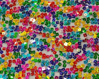 May include: A close-up of a fabric with iridescent square sequins in a rainbow of colors. The sequins are sewn onto a mesh fabric.
