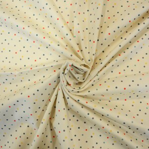 May include: Cream-colored fabric with a repeating pattern of small, colorful polka dots. The dots are red, yellow, blue, and gray.