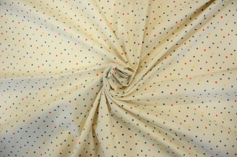 May include: Cream-colored fabric with a repeating pattern of small, colorful polka dots. The dots are red, yellow, blue, and gray.