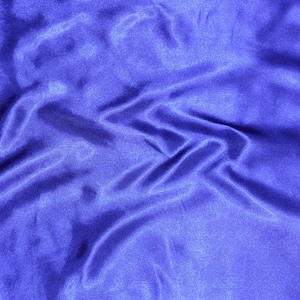 May include: A close-up of a smooth, blue satin fabric with soft folds and wrinkles.