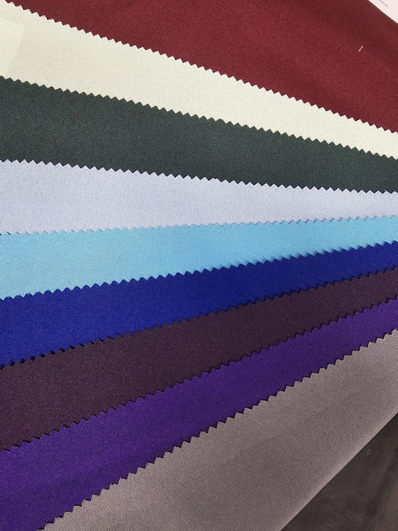 Puede incluir: Una colecci&oacute;n de muestras de tela en varios colores, incluyendo burdeos, crema, verde oscuro, azul claro, azul cielo, azul real, morado y gris.
