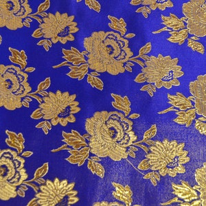 May include: Blue fabric with a gold floral pattern. The fabric has a brocade texture and features a repeating pattern of stylized flowers and leaves.