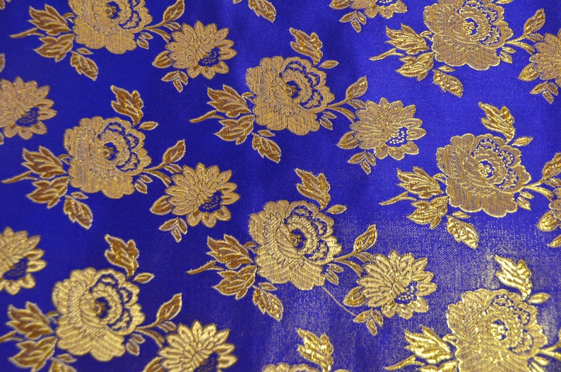 May include: Blue fabric with a gold floral pattern. The fabric has a brocade texture and features a repeating pattern of stylized flowers and leaves.