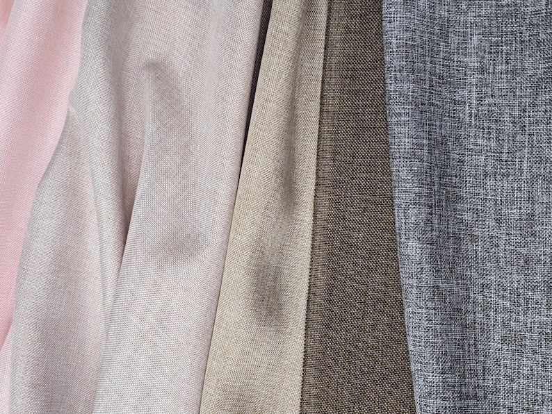 May include: Close-up of various fabric swatches in shades of pink, beige, and gray. The fabrics have a textured appearance, with visible woven patterns. The colors range from light pink to a deep brown and a textured gray.
