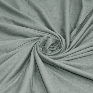 May include: A close-up of a soft, gray fabric with a smooth texture. The fabric is folded and twisted, creating a swirling pattern.