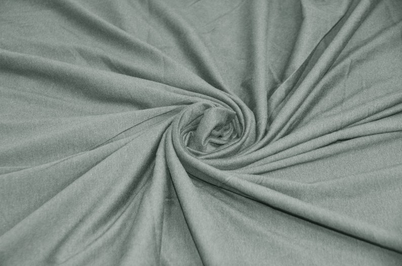 May include: A close-up of a soft, gray fabric with a smooth texture. The fabric is folded and twisted, creating a swirling pattern.