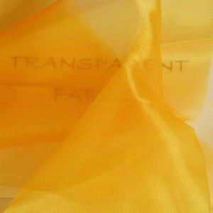 May include: A piece of yellow sheer fabric with the words "TRANSPARENT FABRIC" written on it.
