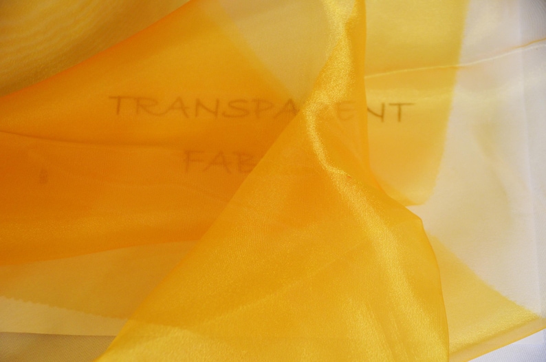 May include: A piece of yellow sheer fabric with the words "TRANSPARENT FABRIC" written on it.