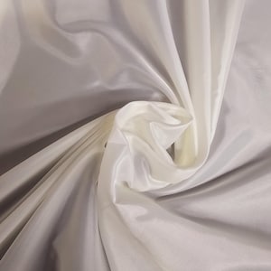 Puede incluir: Tela blanca transparente con una textura suave y sedosa. La tela est&aacute; drapeada y doblada, mostrando su naturaleza fluida y delicada.