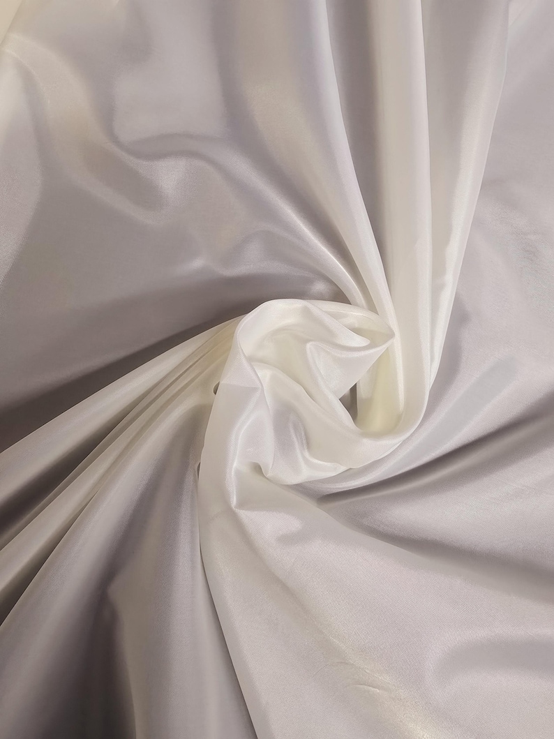 Puede incluir: Tela blanca transparente con una textura suave y sedosa. La tela est&aacute; drapeada y doblada, mostrando su naturaleza fluida y delicada.