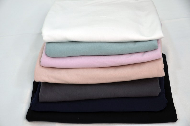 May include: A stack of seven fabric swatches in various colors, including white, light blue, pink, peach, gray, navy blue, and black.