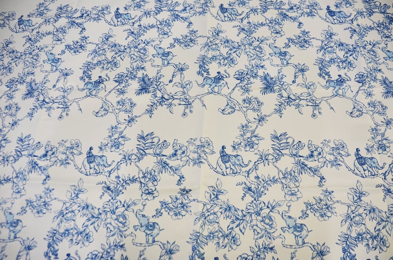 May include: White fabric with a blue and white repeating pattern of elephants, monkeys, and peacocks in a jungle setting.