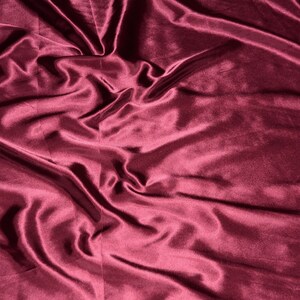 May include: A close-up of a deep burgundy satin fabric with soft, flowing folds and a smooth, luxurious texture.